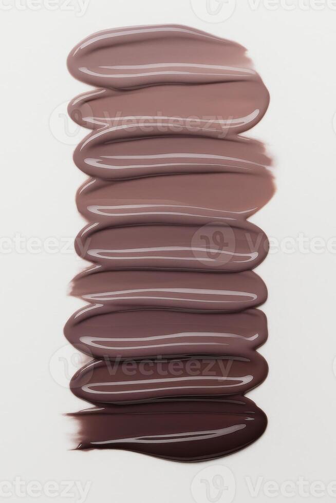 Smooth overlapping strokes of brown nail polish in a vertical gradient, from light mocha to dark chocolate tones, each swatch glossy and richly pigmented. photo