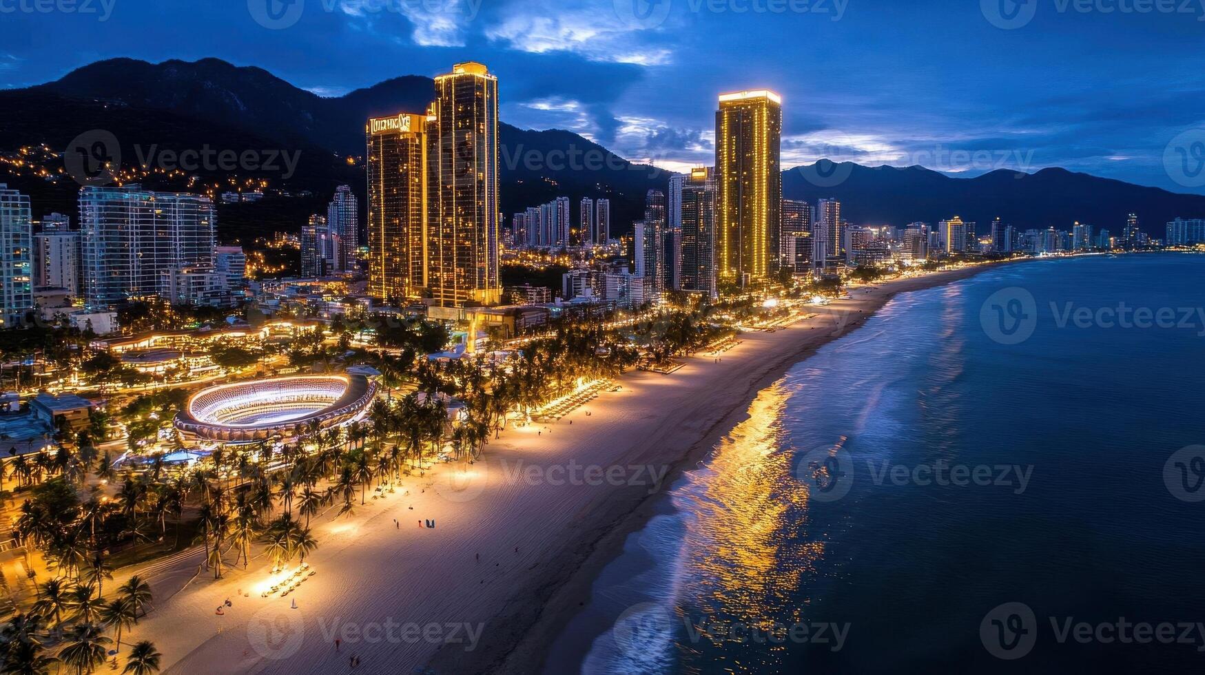 A stunning beachfront cityscape illuminated at night, with golden lights reflecting on the calm ocean and luxury high-rise buildings photo