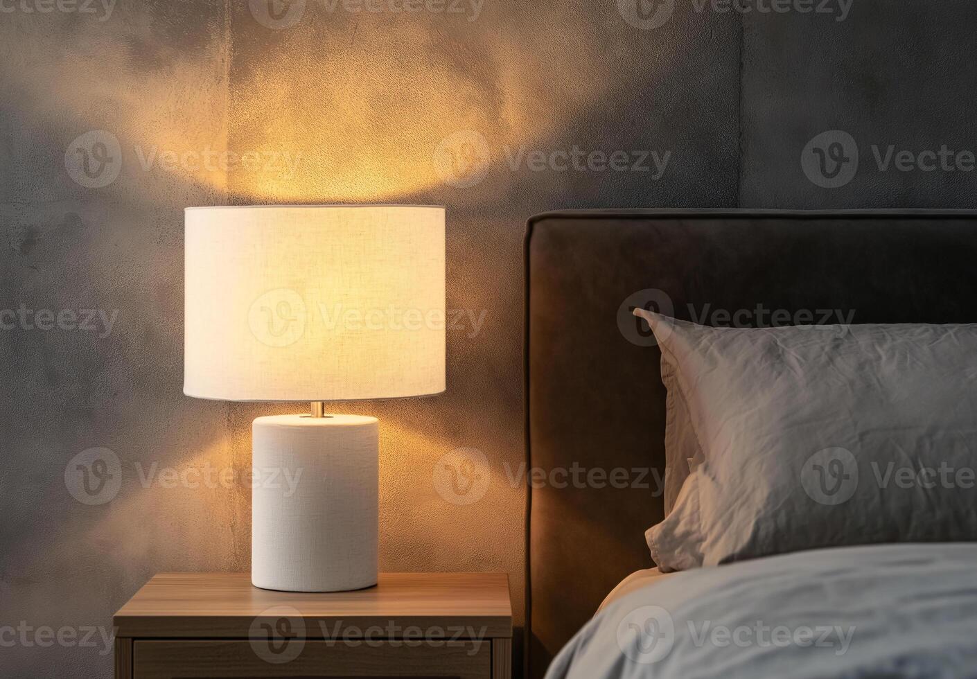 A lamp is lit up on a bedside table photo