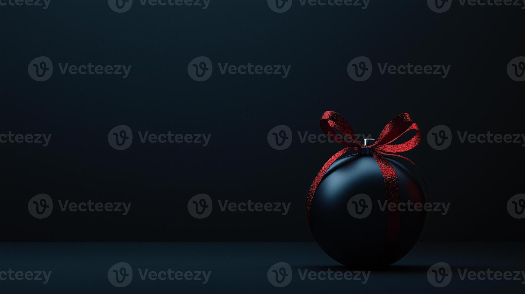 A black ball with a red ribbon on it sits on a dark background photo