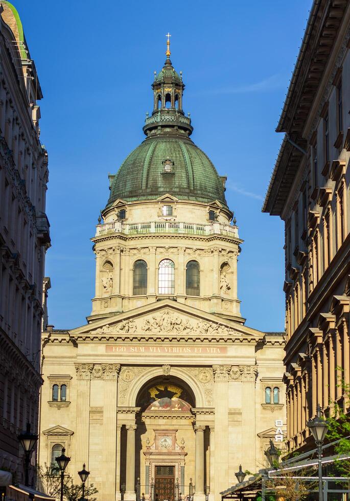 St. Stephen's Basilica dome and entrance viewed from narrow street in Budapest, Hungary, under clear blue sky, photographed on April 14, 2024 photo