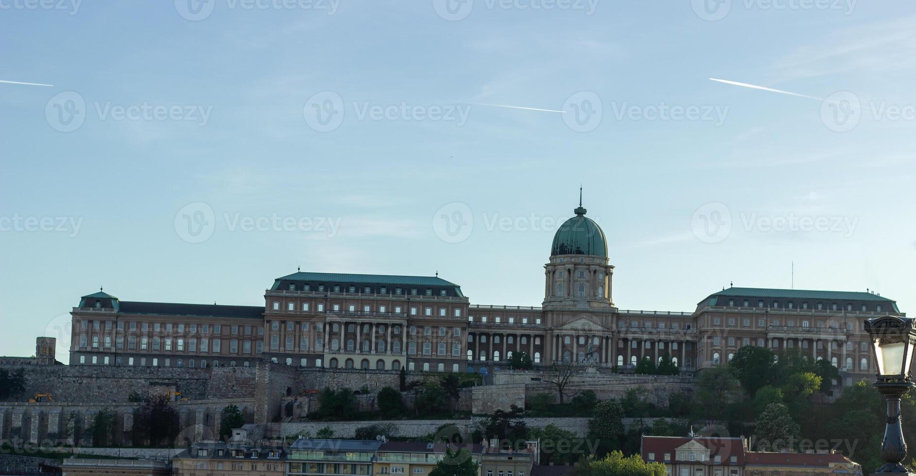 Panoramic view of Buda Castle in Budapest, Hungary, with green dome and historic architecture on hilltop, surrounded by stone walls and greenery photo
