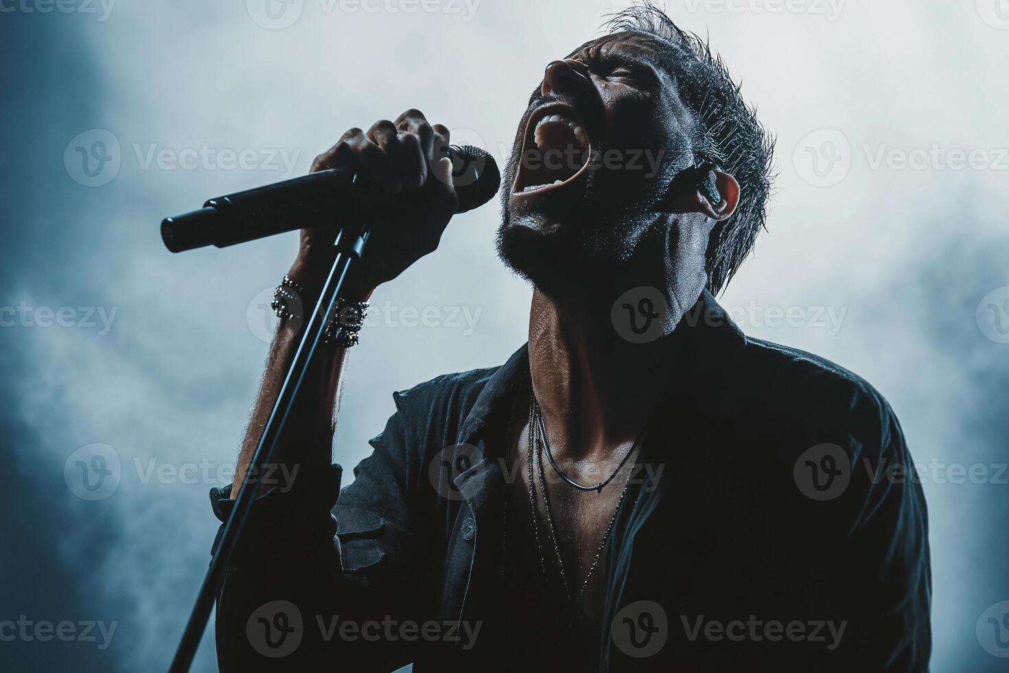 A man singing into a microphone in front of a blue background photo