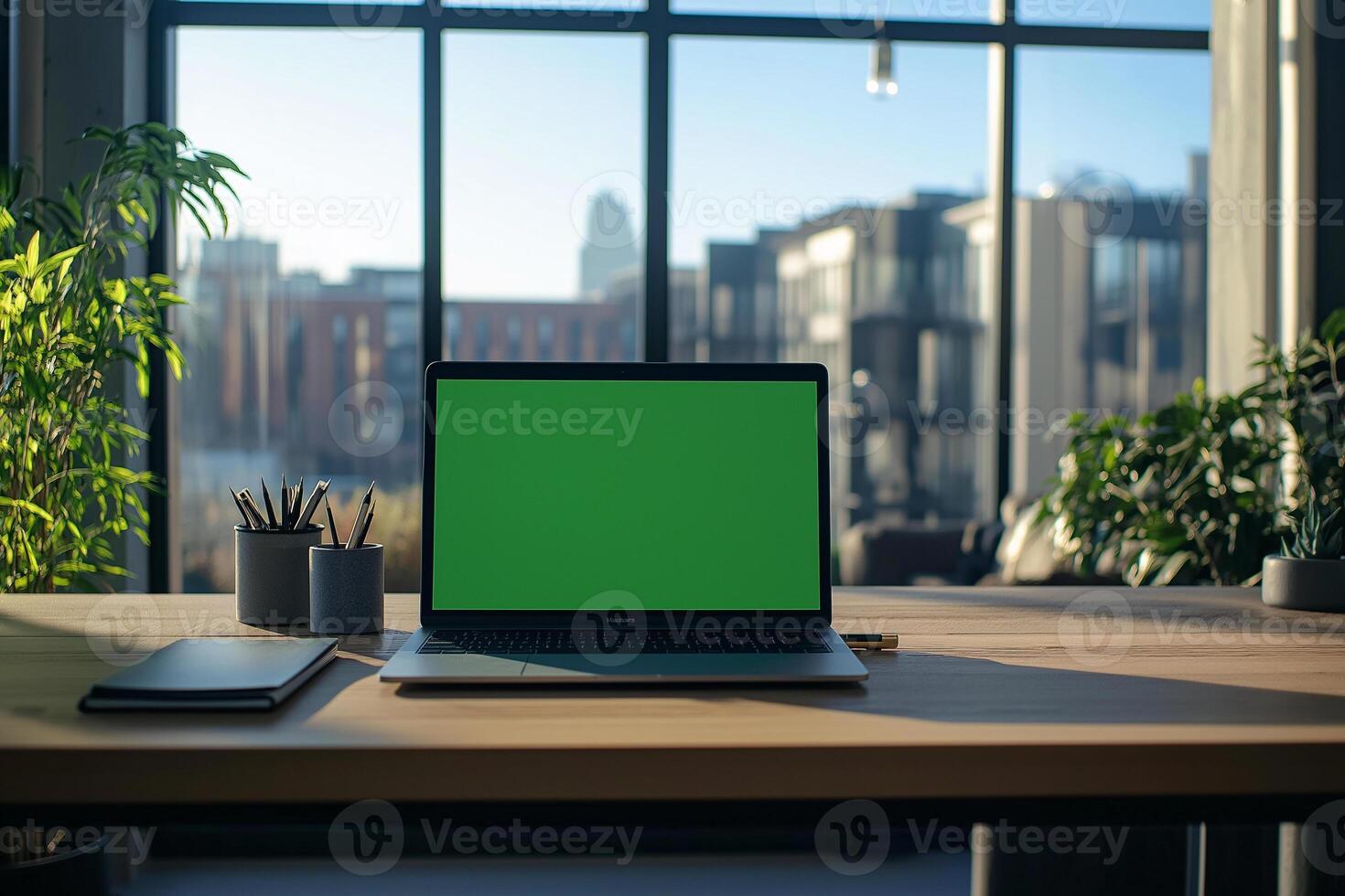Laptop with green screen on desk in office with window photo
