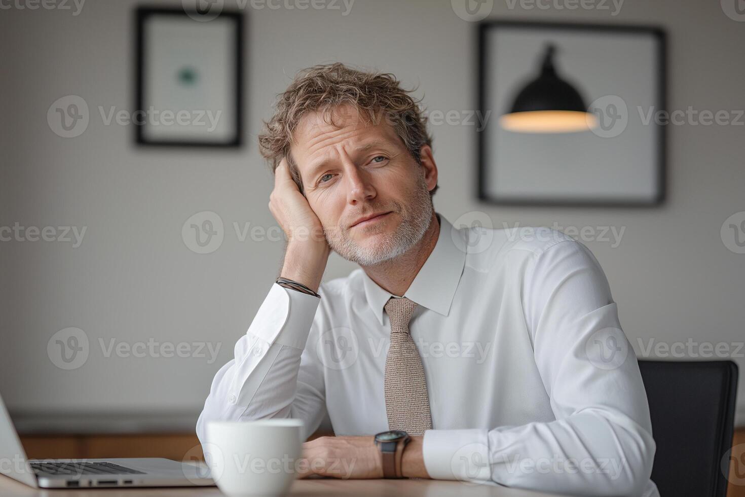 A man in a shirt and tie sitting at a table with a laptop photo