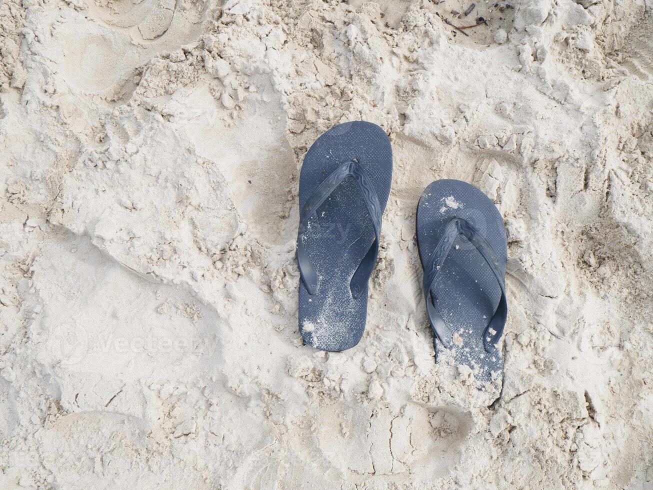 A pair of blue flip flops on a sandy beach photo