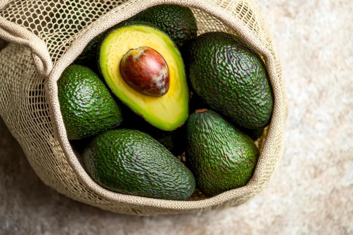 Avocados in a mesh bag on a textured surface. photo