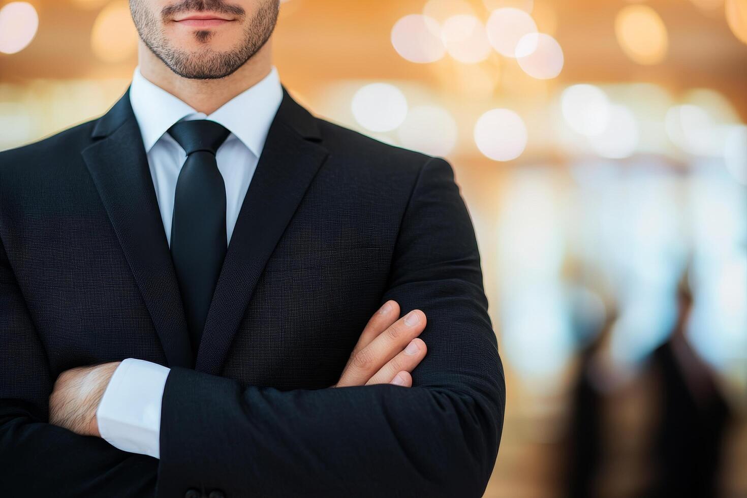 Confident man in suit with arms crossed in a blurred background setting. photo