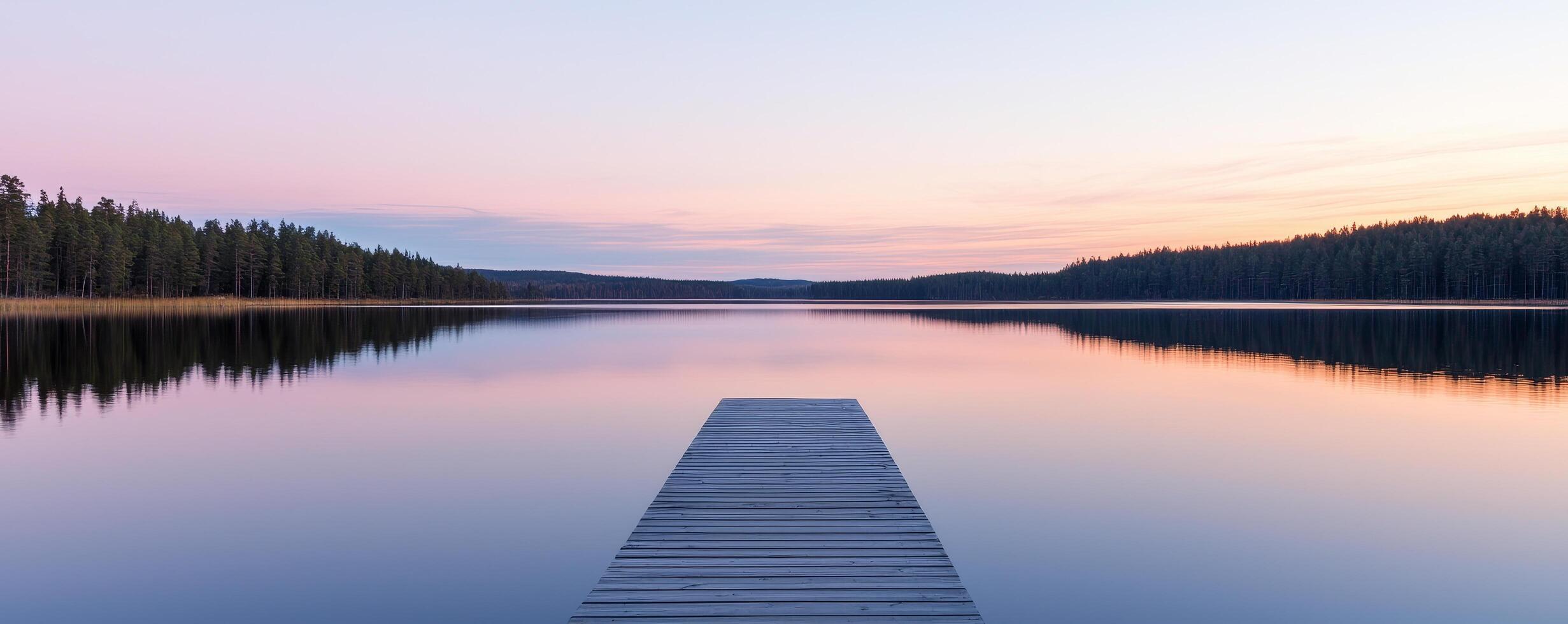 Tranquil lake at sunset with a wooden dock extending into calm waters. photo