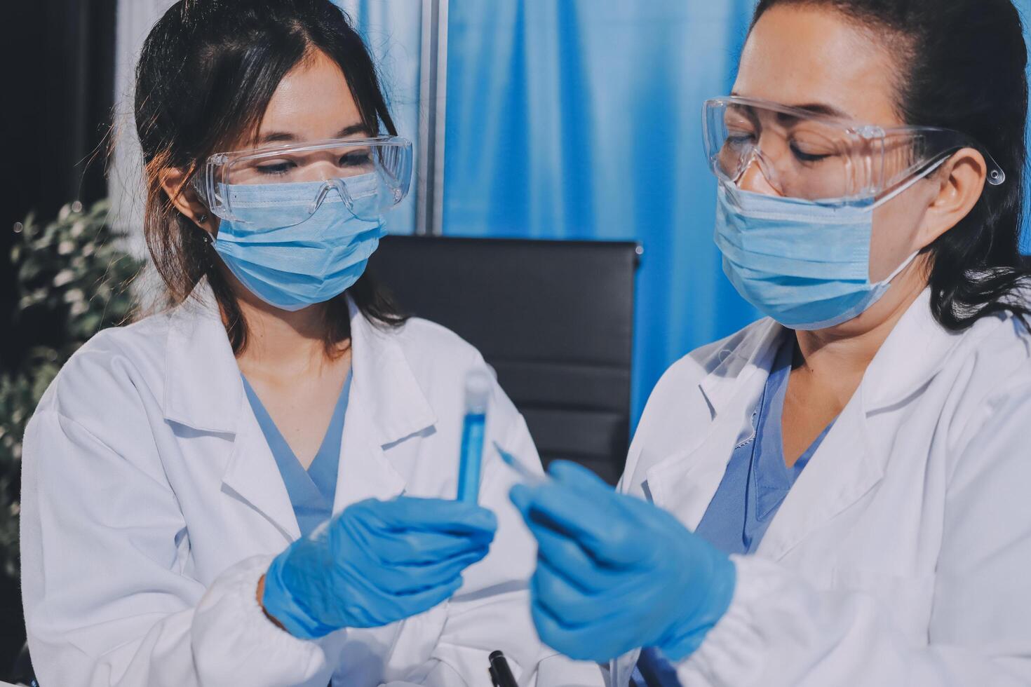 Two women in lab coats holding a vial of blood photo