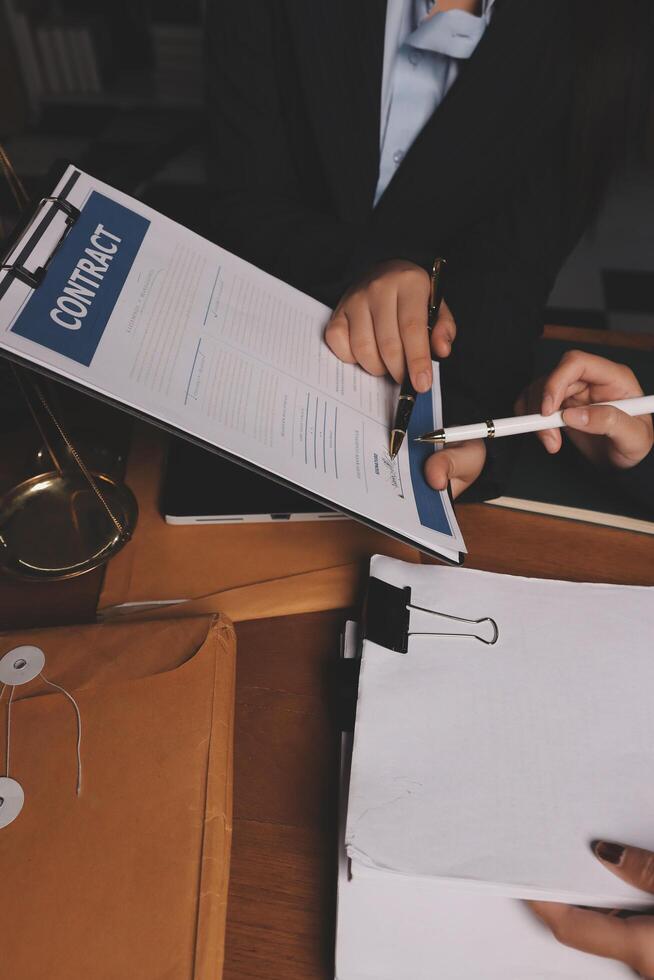 A man in a suit is signing paperwork with a pen photo