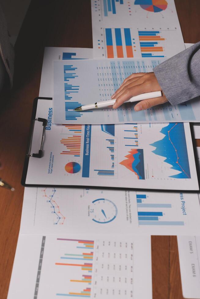 A person is looking at graphs and papers on a desk photo