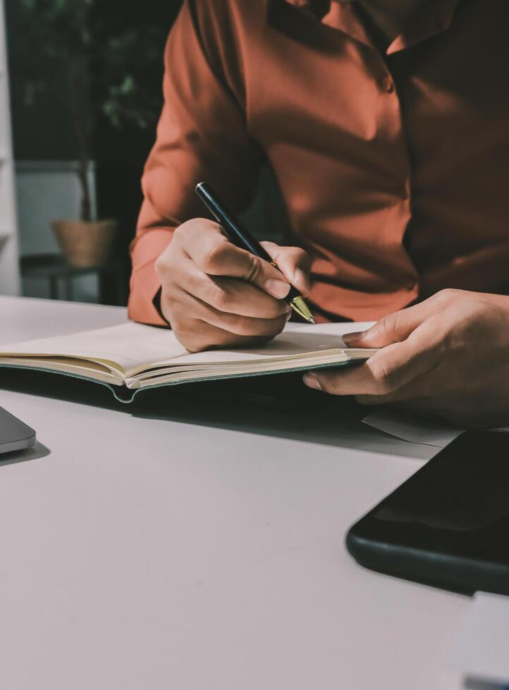 Businessman writing in notebook on desk photo