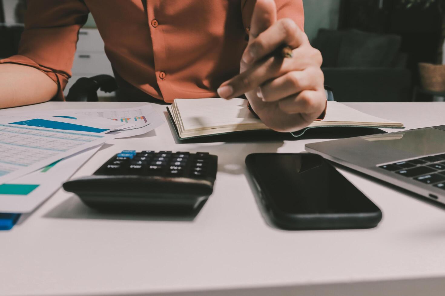 A woman is using a calculator and a laptop to make a business plan photo