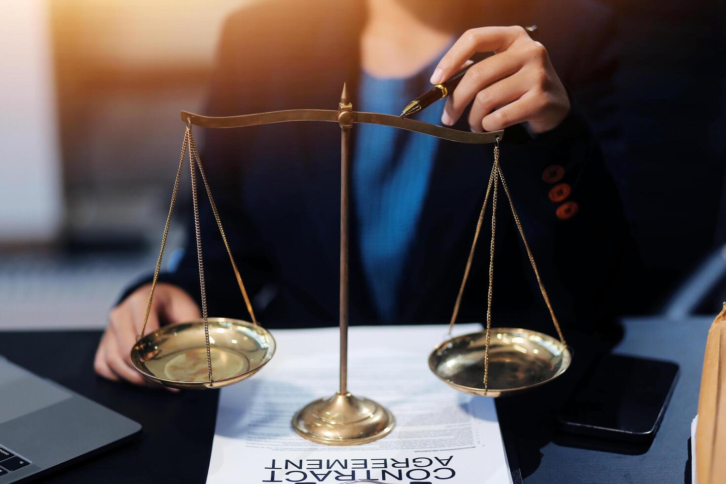 Businesswoman holding scales of justice on desk with laptop photo