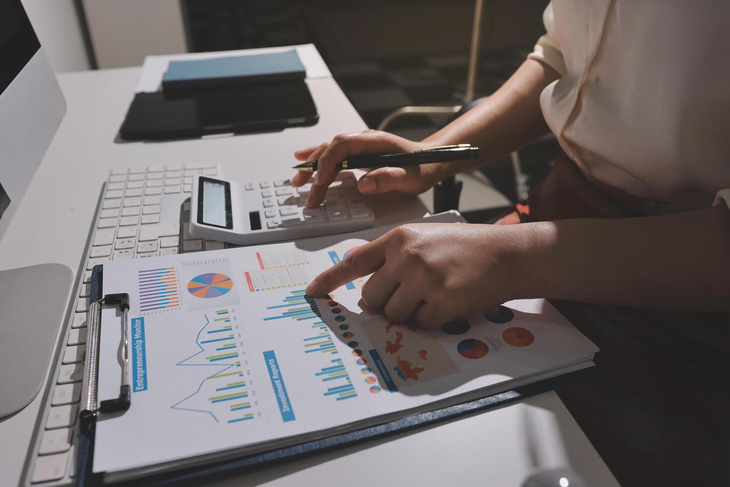 A person is using a calculator and pen to write on a clipboard photo