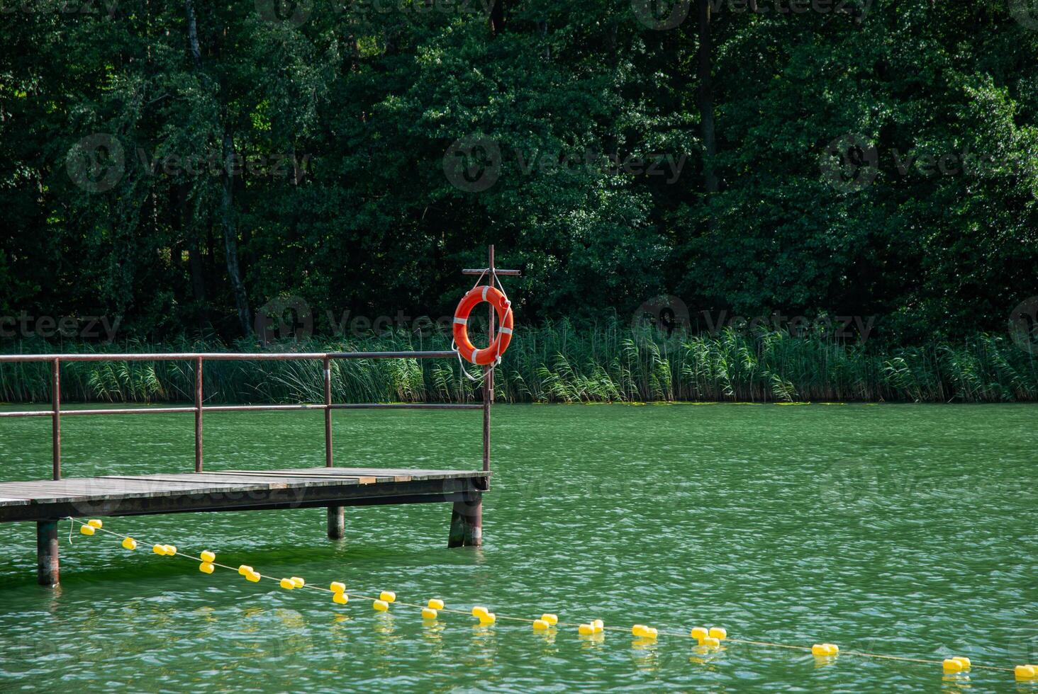 Serene lakeside scene with wooden dock and life buoy in summer. Weekend concept near the forest and lake photo