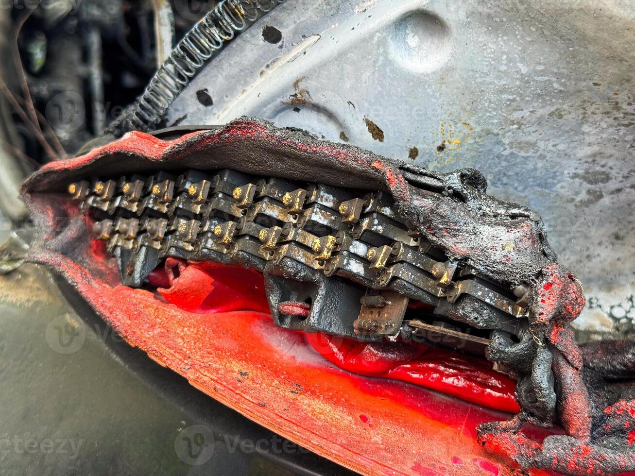 Close-up of a severely burned LED tail light module from a car, showing melted plastic housing, exposed electrical components, and heat-damaged internal structure photo