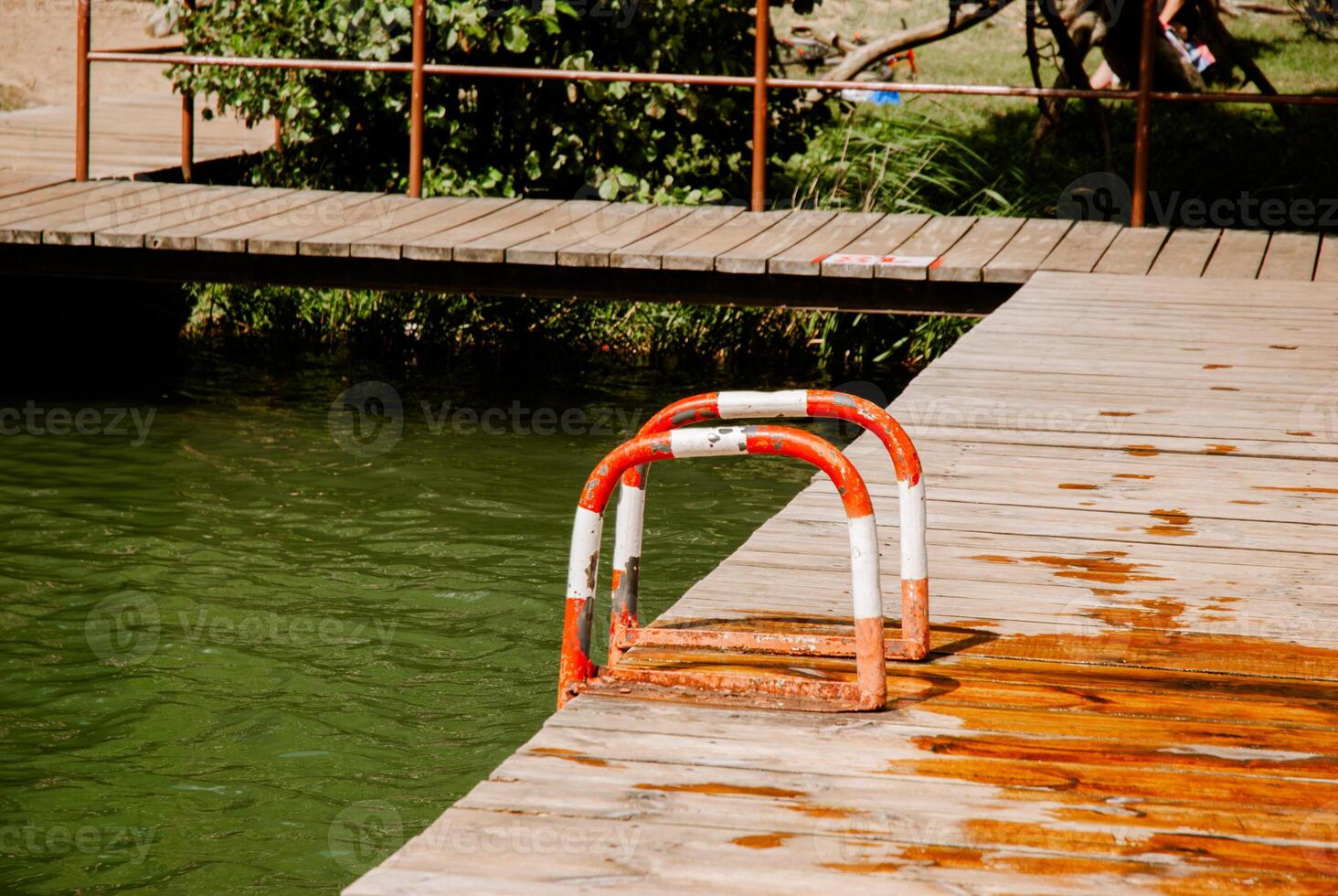 Tranquil lakeside scene with wooden dock and ladder on a sunny day. Weekend concept near the forest and lake photo