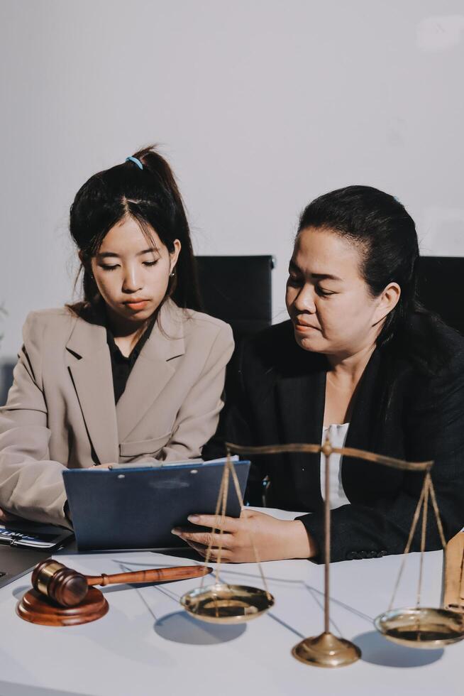 Two businesswomen in suits sitting at a table with a tablet and scales photo