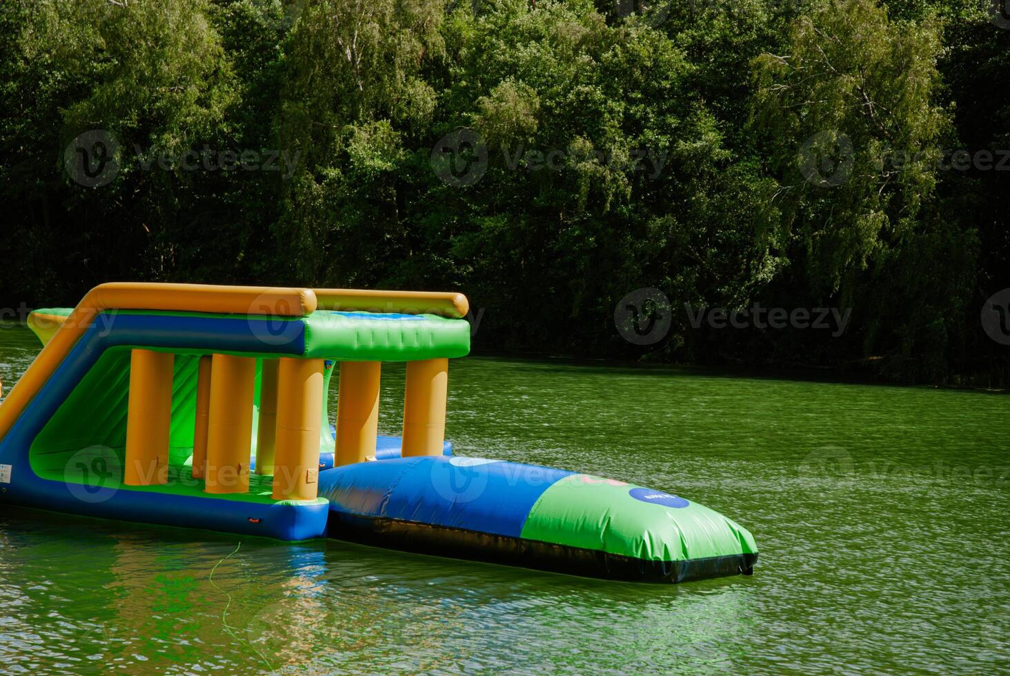 Inflatable water park obstacle course on a lake amidst lush greenery. Weekend concept near the forest and lake photo
