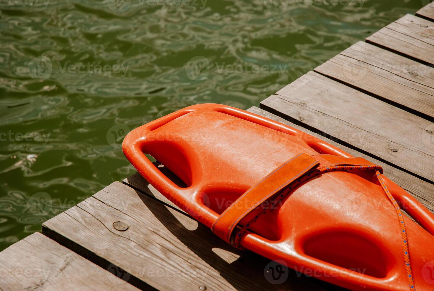 Lifeguard rescue float on wooden dock by calm lake water. Weekend concept near the forest and lake photo