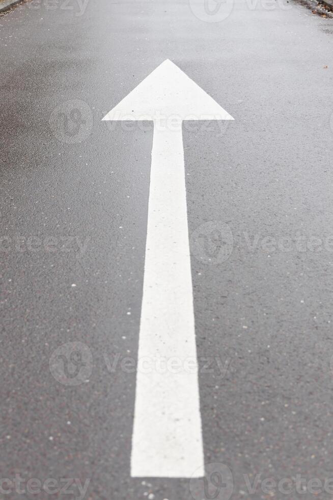 White arrow symbol in a straight direction on an asphalted avenue, transport concept photo