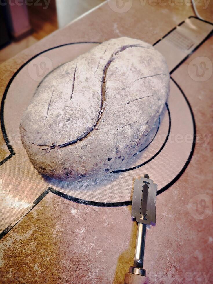 unbaked artisanal sourdough bread freshly scored with a razor before baking on silicone mat photo