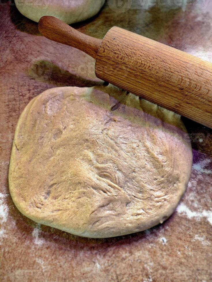 flat rolled khychiny dough with onion, cheese, and potato filling, ready to be rolled with a rolling pin on a prep surface photo