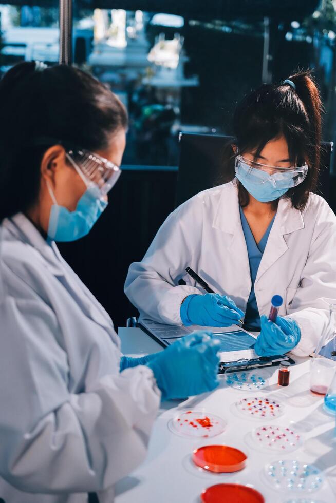 Three women in lab coats and masks working on a project photo