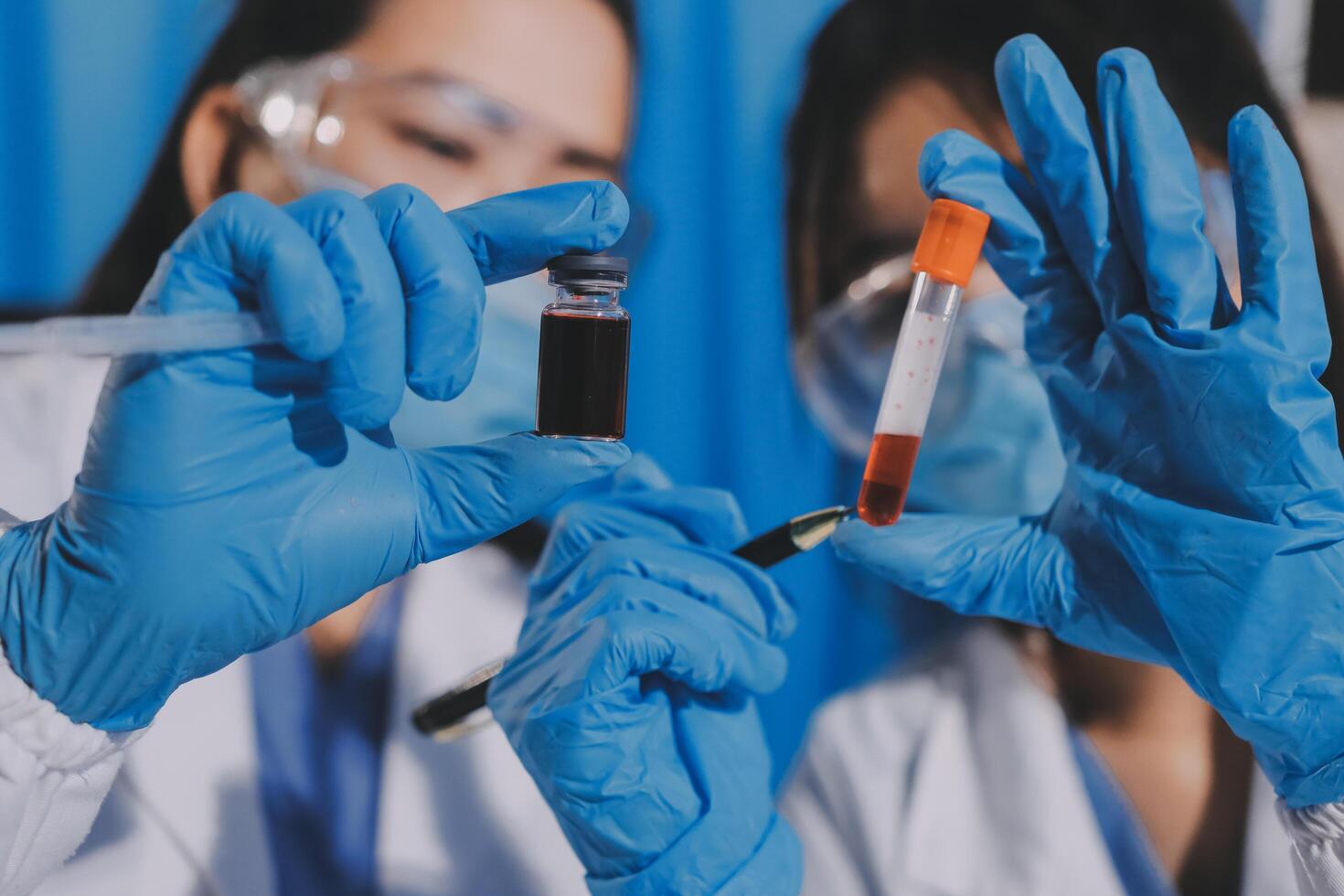 Two people in lab coats holding up a vial photo