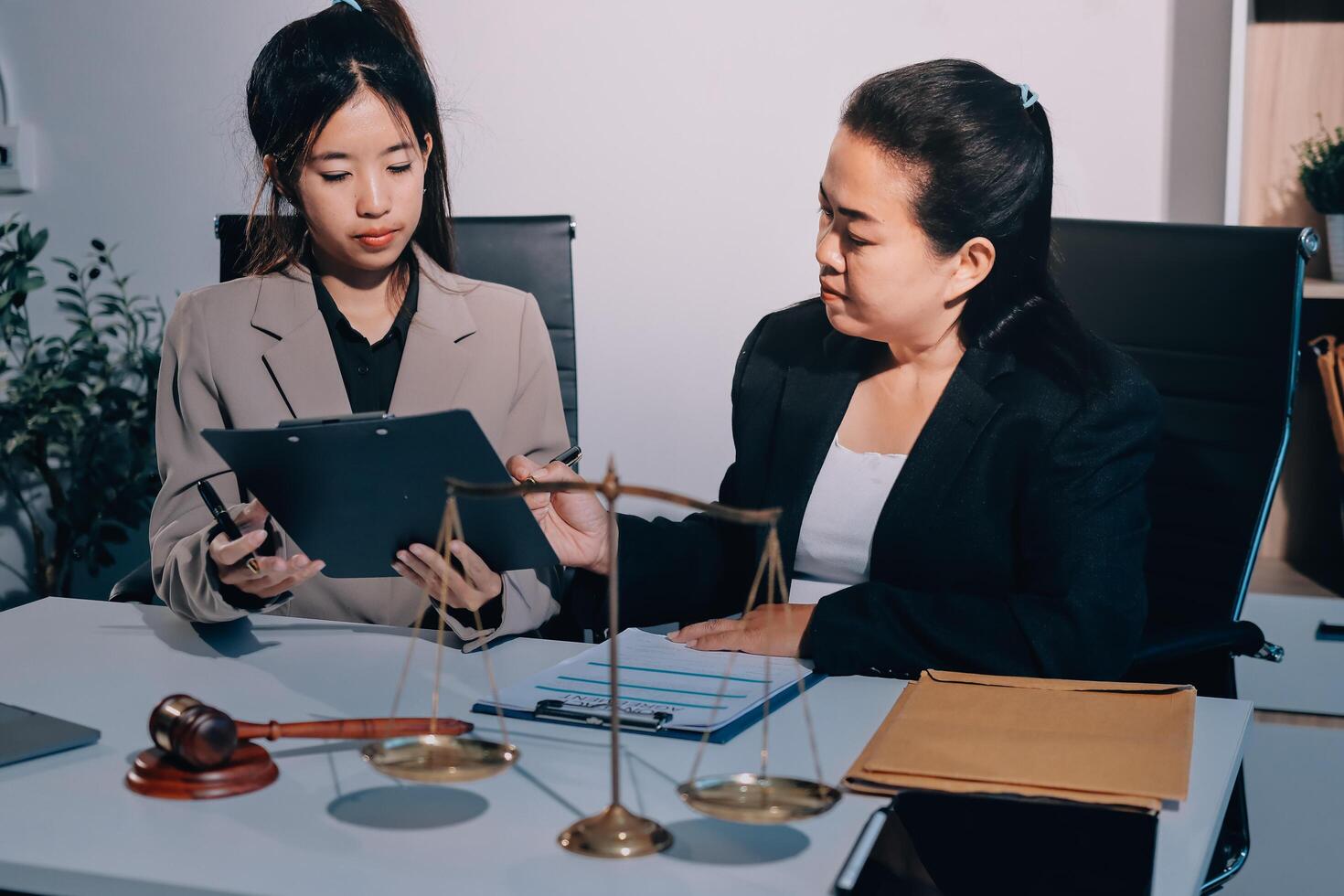 Two businesswomen sitting at a desk with a laptop and a scale photo