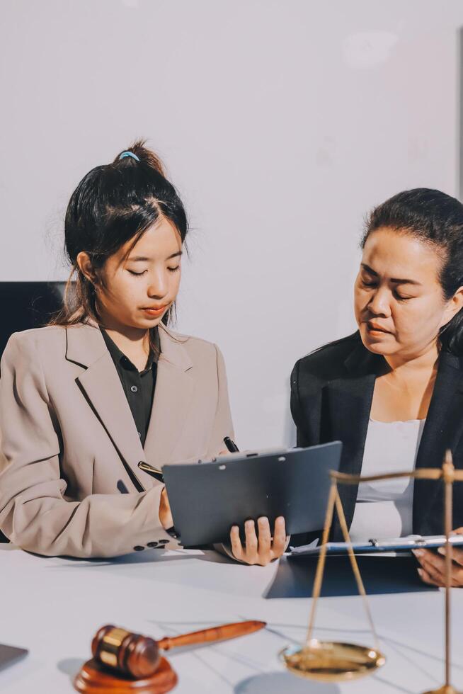 Two business women in suits sitting at a desk with a laptop photo