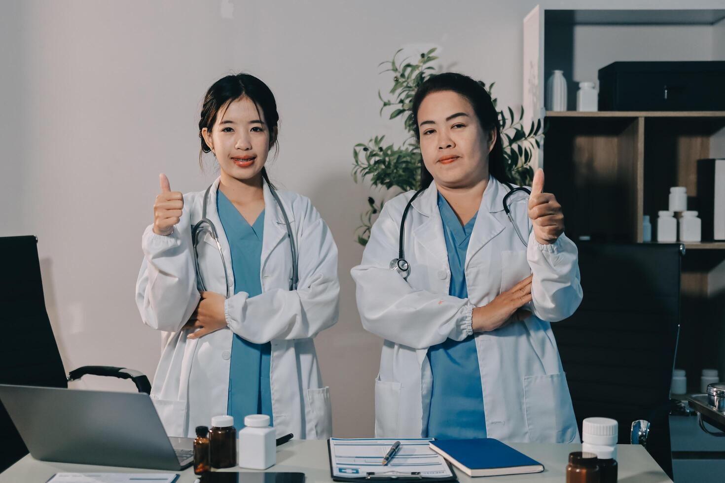 Two female doctors standing in front of a desk with thumbs up photo