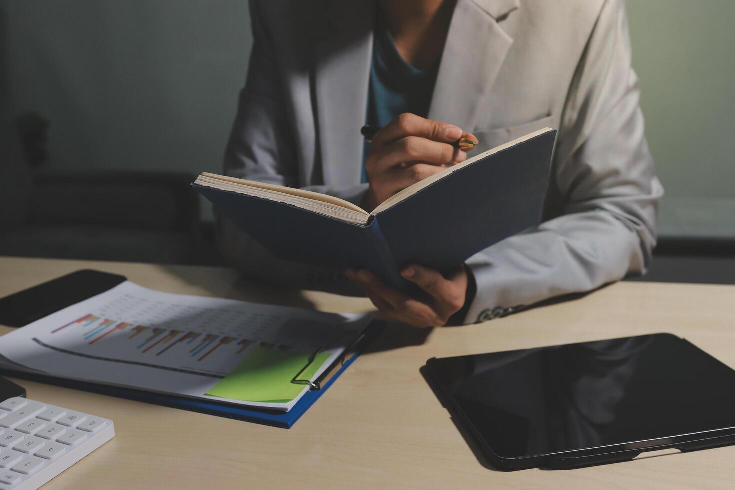 A person in a suit is writing in a book photo