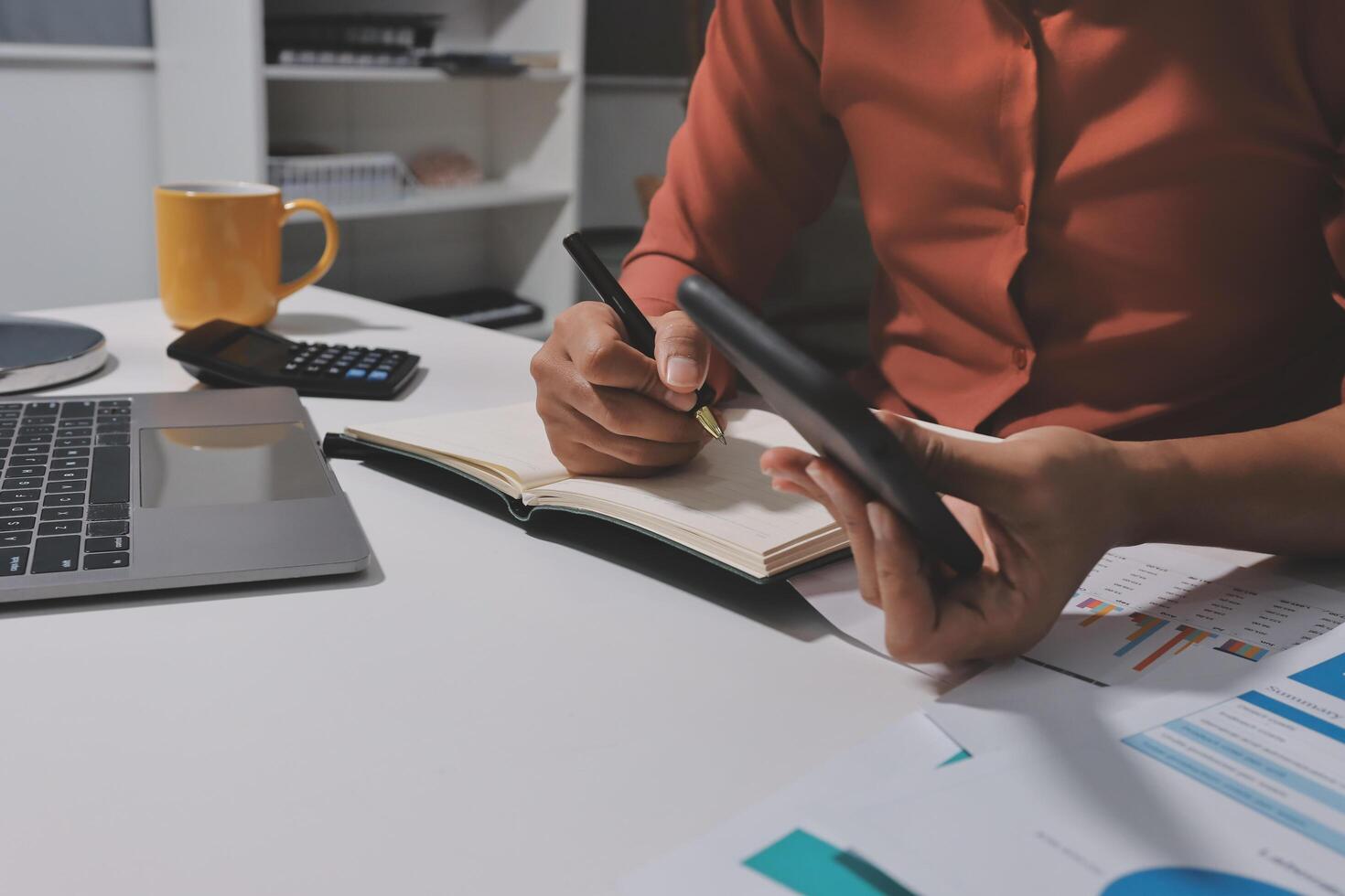 Businessman writing on notebook and using calculator photo