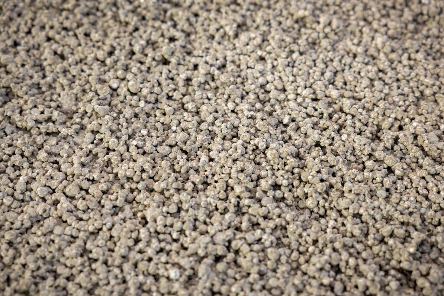 A detailed view of small, uniformly sized granules in light gray, showcasing a rough texture. The material appears suitable for construction use. photo