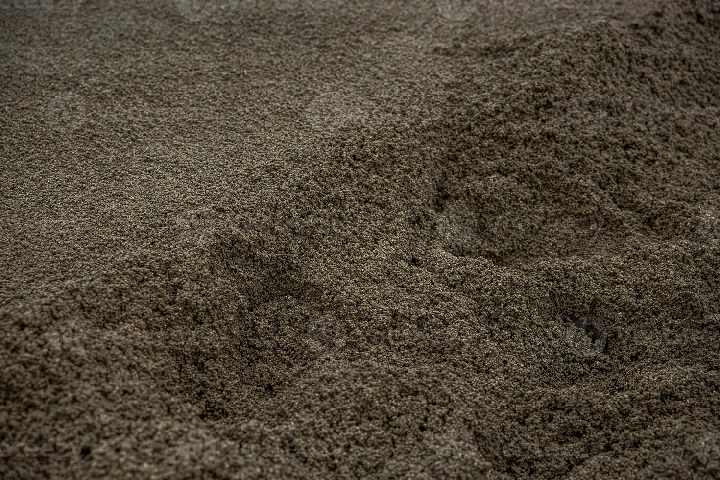 A detailed view of dark gray granular material with uneven ridges and depressions, highlighting the texture and natural patterns of the surface. photo