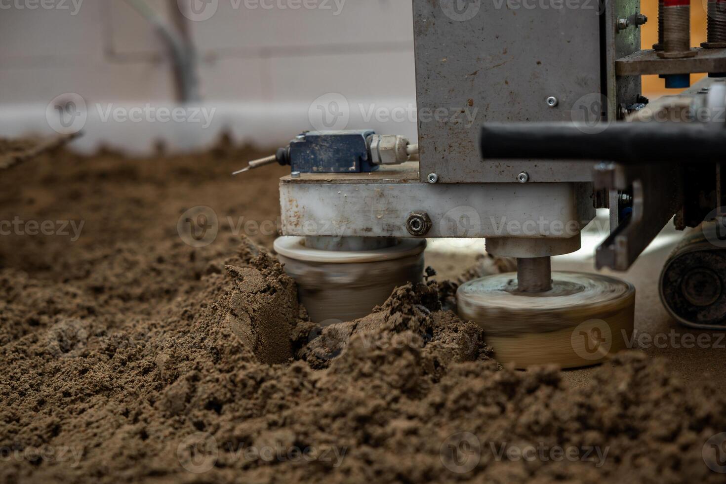 Close up of a machine leveling Estrich concrete over underfloor heating pipes at an indoor construction site with visible piping and white walls. photo