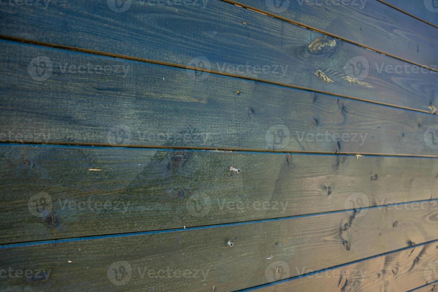 A detailed view of a wooden wall featuring horizontal planks with a dark, weathered finish. The surface shows grain patterns, knots, and subtle imperfections. photo