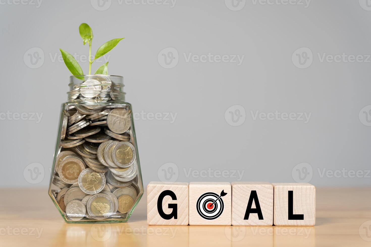 A glass bottle filled with coins and wooden blocks and the word GOAL symbolizes photo
