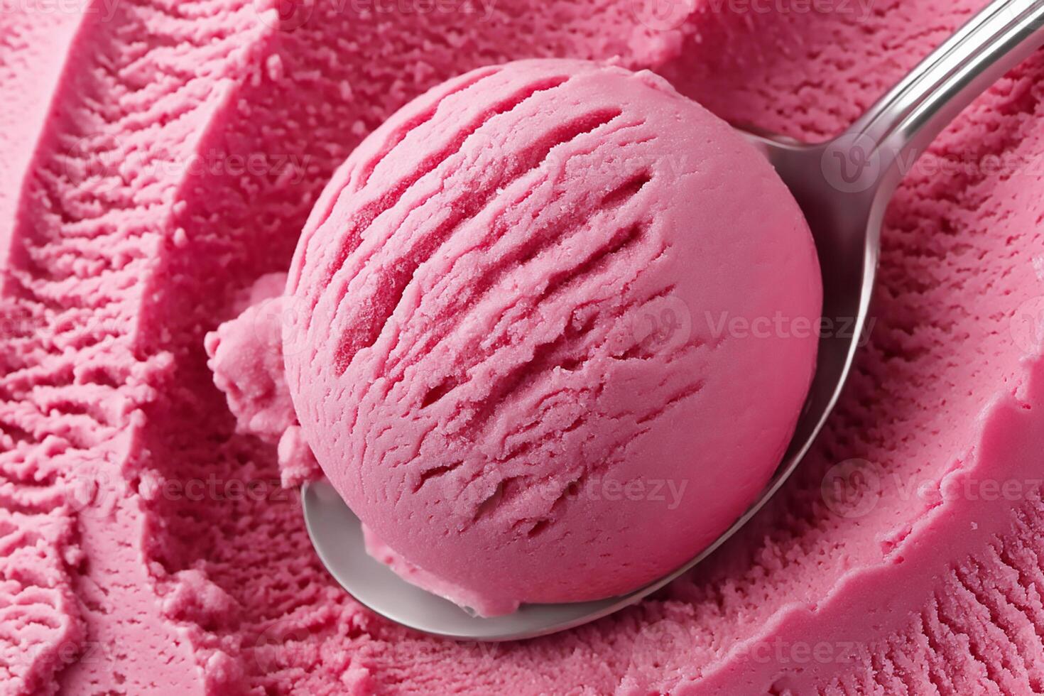 Scoop of pink ice cream served with a silver spoon resting on a creamy surface in a dessert display photo