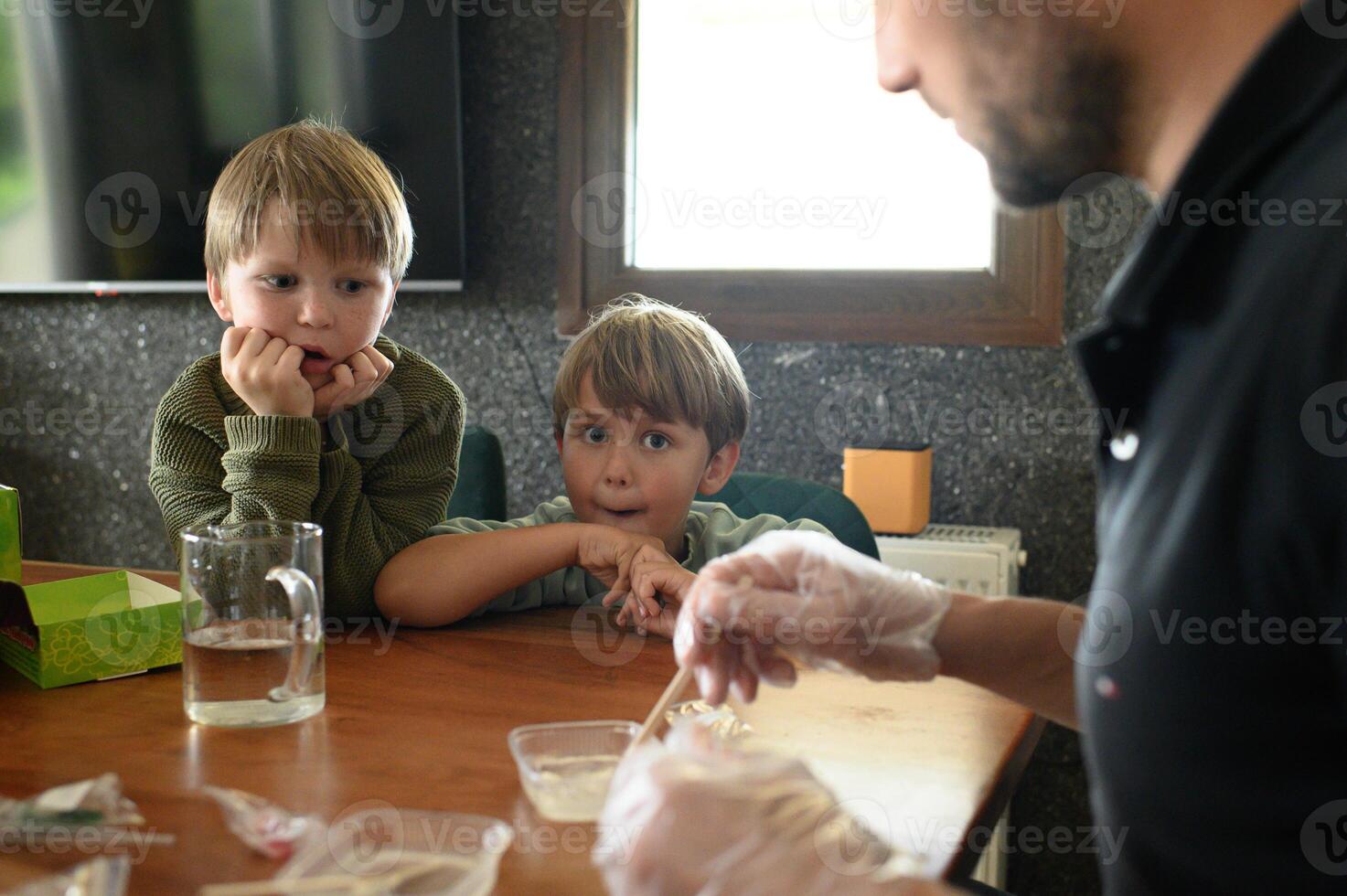 Playful and educational science time father helps kids do safe experiments at kitchen table. Children full of wonder. photo