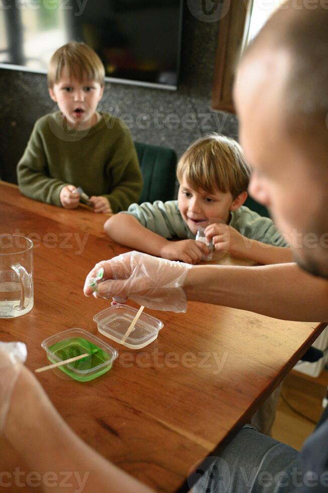 Close-up of kids amazed faces as bubbling flask reacts. Father helps them explore science with joy. photo
