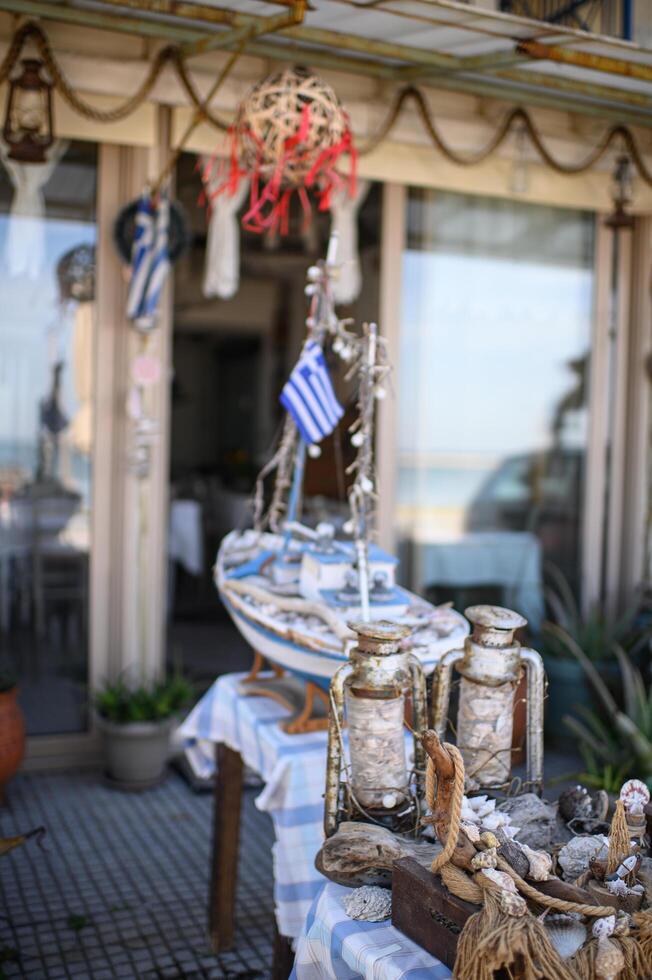 A charming Greek cafe decorated in a nautical style, featuring blue and white colors, seashells, and fishing nets. photo