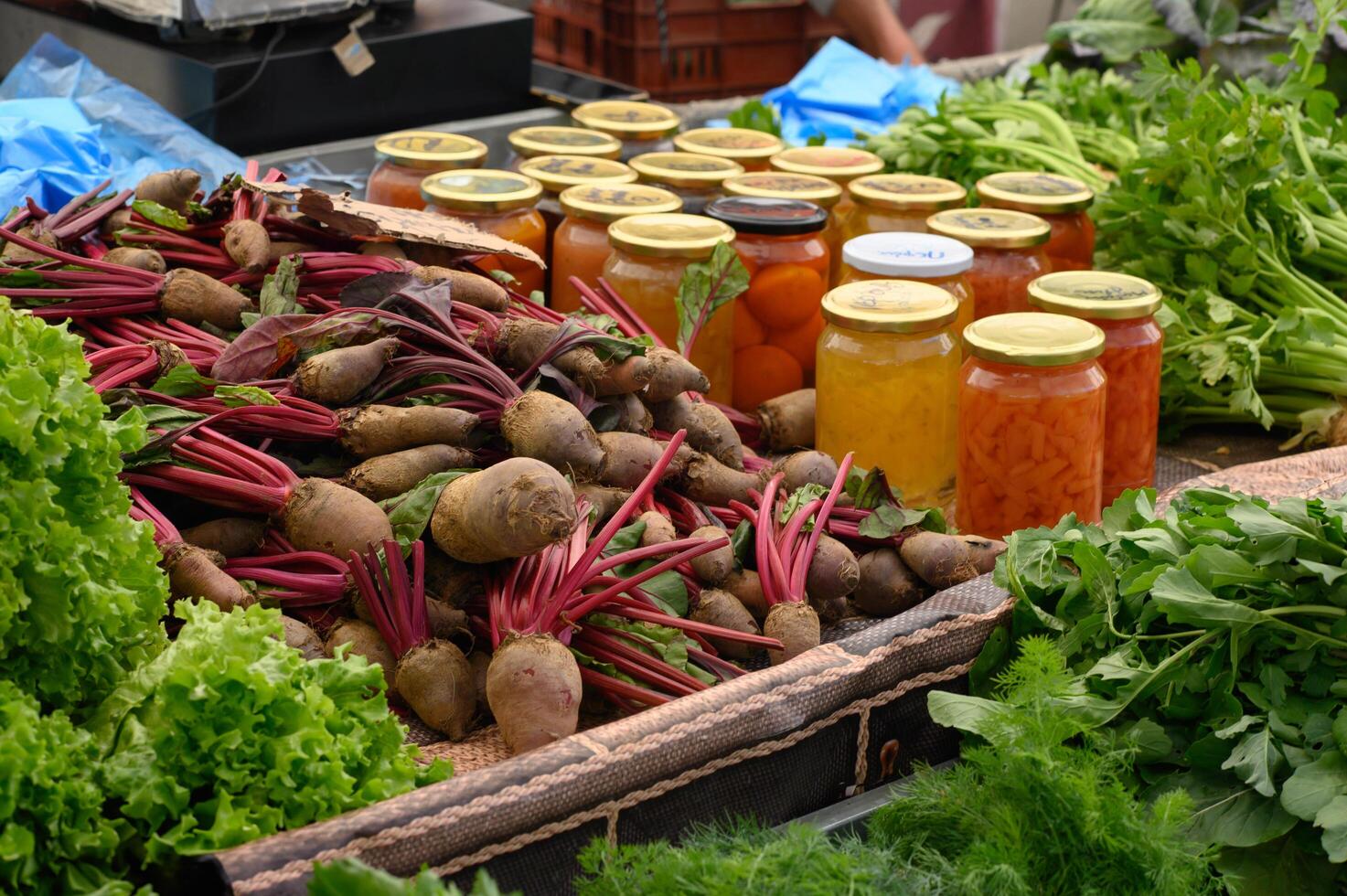 An assortment of honey, pickled vegetables, and fruit jams in glass jars, glowing under the market lights. photo