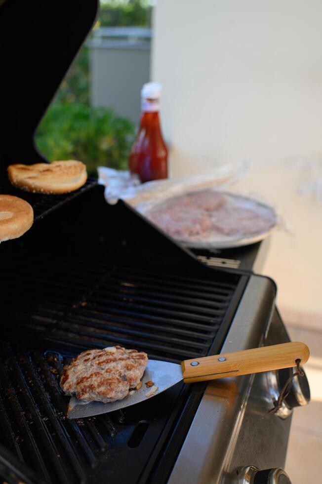 A juicy burger patty sizzles on the grill, resting on a spatula ready to be flipped photo