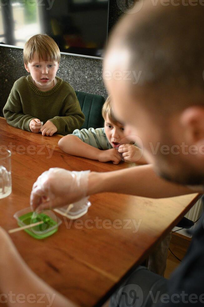 Father encourages hands-on learning with simple home chemistry. Kids engaged, joyful and curious at every step. photo