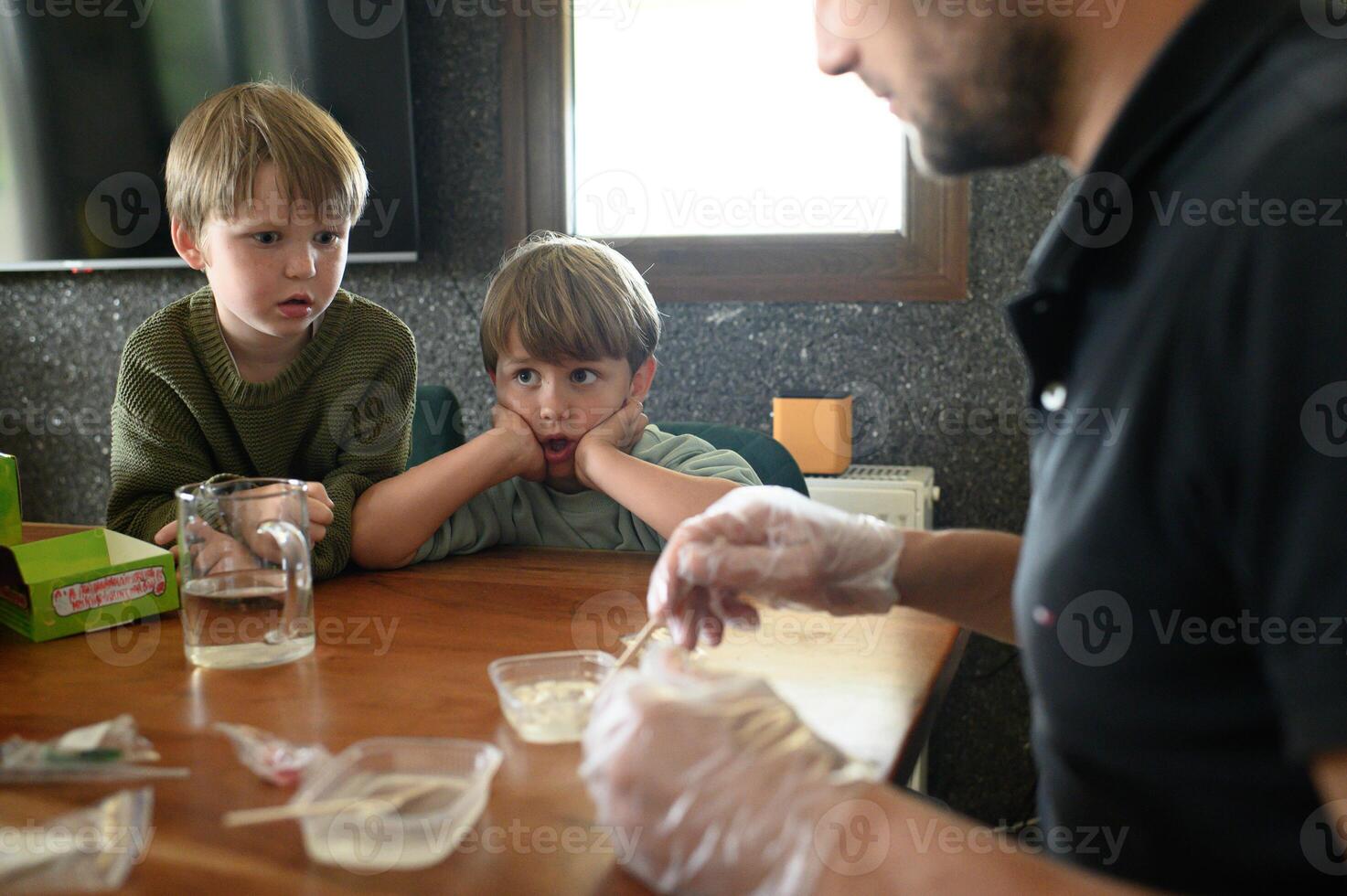 Indoor science project dad and kids work with pipettes, food coloring and water. Surprised and happy reactions follow. photo
