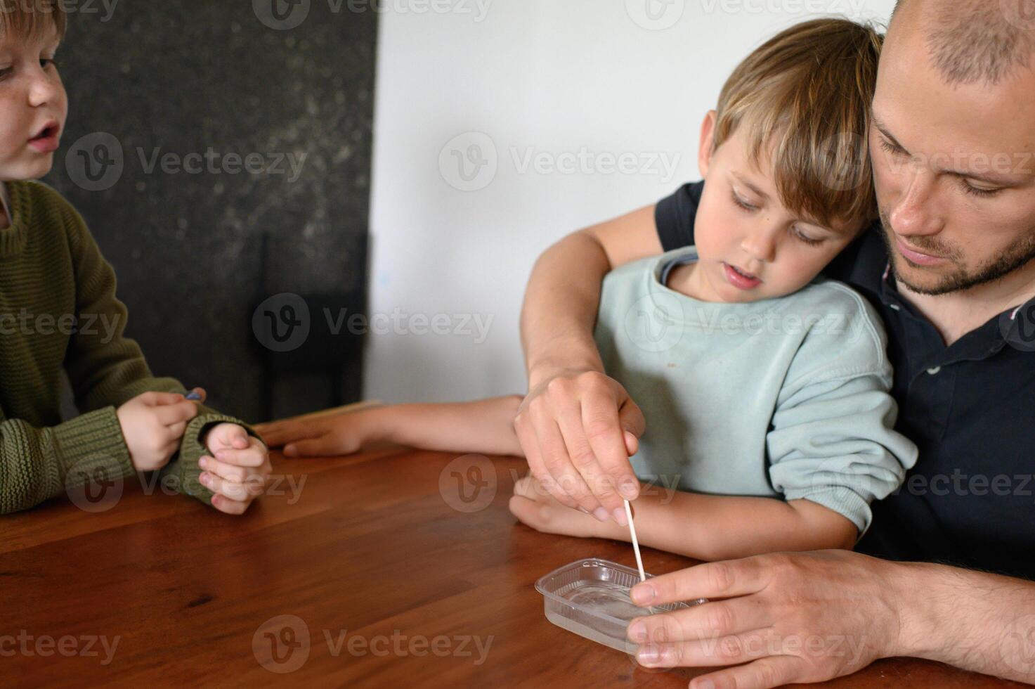 Curious children and dad explore home science with flasks and pipettes. Learning through play, fun and awe in their expressions. photo